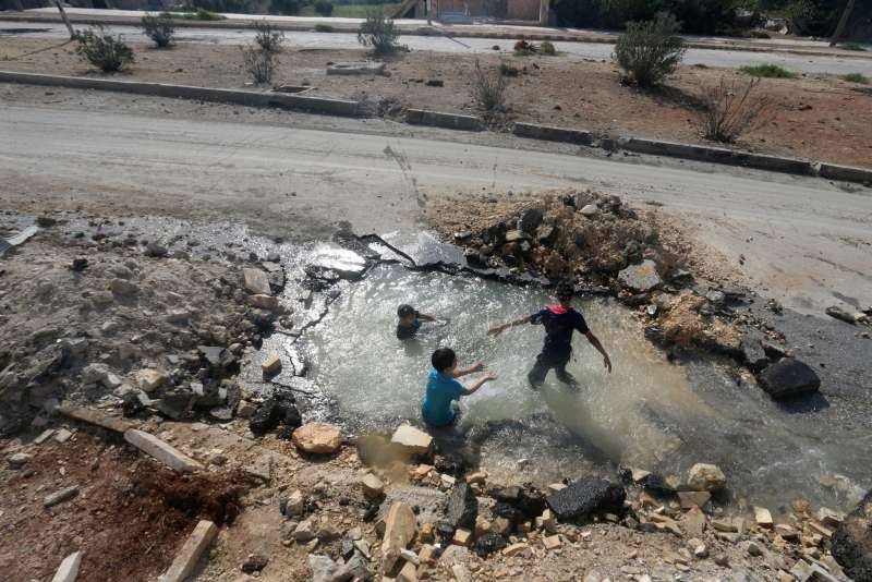 Boys Playing In Water From A Pipe Damaged By Shelling In Aleppo Last Month