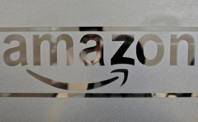 FILE PHOTO: Employees Of Amazon India Are Seen Behind A Glass Bearing The Company's Logo Inside Its Office In Bengaluru