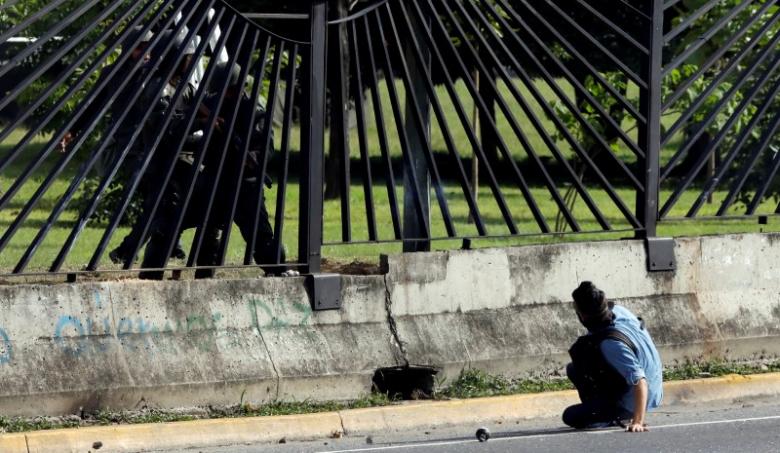 A Member Of The Riot Security Forces Points A Gun Through The Fence Of An Air Force Base At David Jose Vallenilla, Who Was Fatally Injured During Clashes At A Rally Against Venezuelan President Nicolas Maduro's Government In Caracas