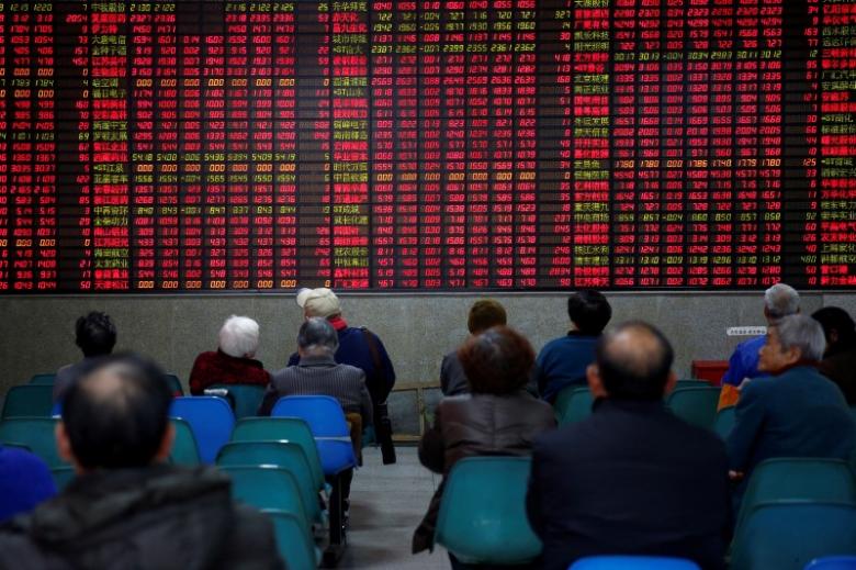 FILE PHOTO: Investors Look At An Electronic Board Showing Stock Information On The First Trading Day After The New Year Holiday At A Brokerage House In Shanghai