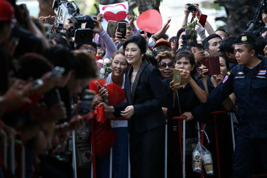 Ousted former thai prime minister yingluck shinawatra greets supporters as she arrives at the supreme court in bangkok