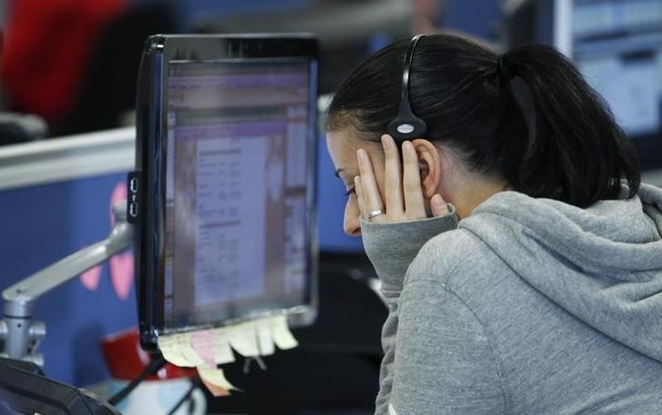 A worker on IG Index's trading floor puts her hand to her face as she speask on the phone while markets tumble, in London